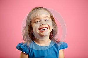 Cheerful little girl with charming smile and hearty laugh on pink isolated background, expresses heartfelt emotions of