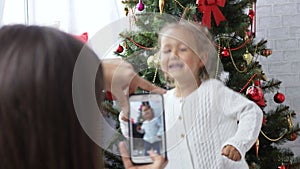 Cheerful little girl dancing and playing the ape near Christmas tree