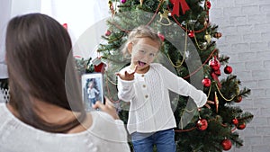 Cheerful little girl dancing and playing the ape near Christmas tree