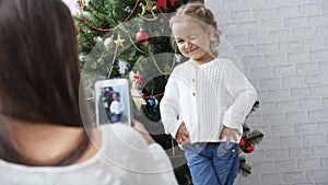 Cheerful little girl dancing and playing the ape near Christmas tree