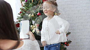 Cheerful little girl dancing and playing the ape near Christmas tree