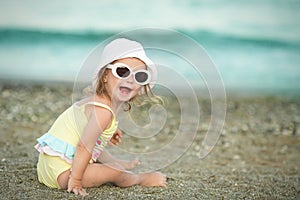 Cheerful little girl with Down syndrome with glasses resting on the sea coast