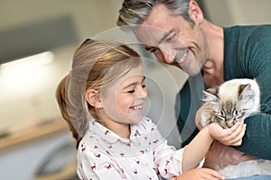 Cheerful little girl feeding cat