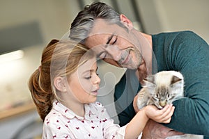 Cheerful little girl feeding cat