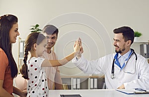 Cheerful little girl giving five to positive young man doctor pediatrician