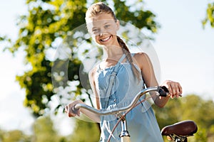 Cheerful little girl holding her bicycle