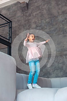 Cheerful little girl laughing while having fun and jumping