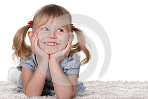 Cheerful little girl lying on the carpet