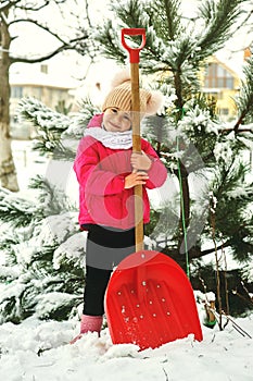 Cheerful little girl playing with a snow shovel