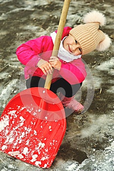 Cheerful little girl playing with a snow shovel