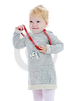 Cheerful little girl put on her big red beads
