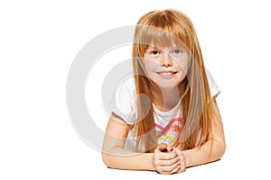 A cheerful little girl with red hair is lying ; isolated on the white