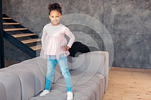 Cheerful little girl standing on the sofa