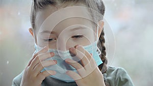 Cheerful little girl tries to put on medical mask for saving health and safety