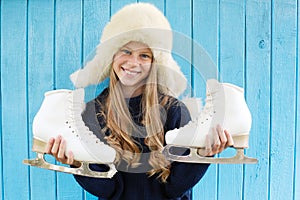 Cheerful little girl in warm sweater and hat keeps figure skates