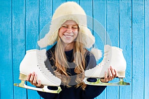 Cheerful little girl in warm sweater and hat keeps figure skates