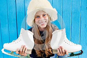 Cheerful little girl in warm sweater and hat keeps figure skates