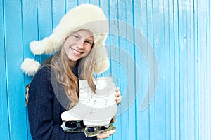 Cheerful little girl in warm sweater and hat keeps figure skates