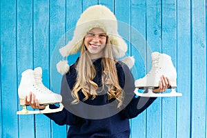 Cheerful little girl in warm sweater and hat keeps figure skates