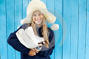 Cheerful little girl in warm sweater and hat keeps figure skates