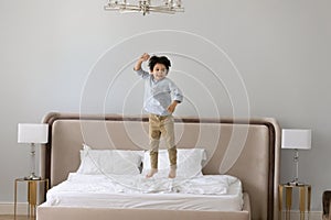 Cheerful little kid boy jumping on bed.