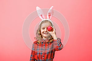 Cheerful little kid girl with bunny ears with an easter egg on a colored background