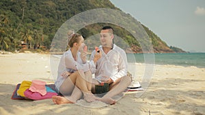 The cheerful love couple holding and eating slices of watermelon on tropical sand beach sea. Romantic lovers two people