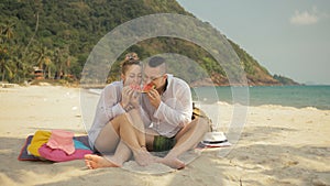 The cheerful love couple holding and eating slices of watermelon on tropical sand beach sea. Romantic lovers two people