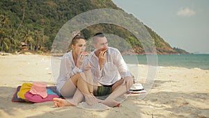 The cheerful love couple holding and eating slices of watermelon on tropical sand beach sea. Romantic lovers two people