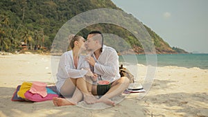 The cheerful love couple holding and eating slices of watermelon on tropical sand beach sea. Romantic lovers two people