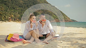 The cheerful love couple holding and eating slices of watermelon on tropical sand beach sea. Romantic lovers two people