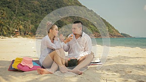 The cheerful love couple holding and eating slices of watermelon on tropical sand beach sea. Romantic lovers two people