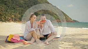 The cheerful love couple holding and eating slices of watermelon on tropical sand beach sea. Romantic lovers two people