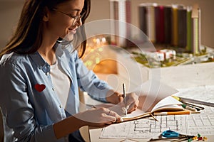 Cheerful lovely business woman gets plasure from architectural work