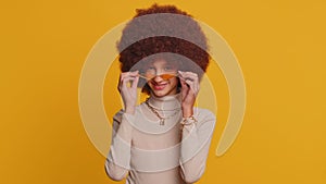 Cheerful lovely young teenager child girl kid smiling, looking at camera on studio yellow background