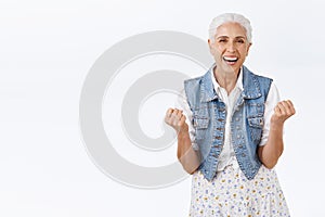 Cheerful, lucky senior woman, granny excited and pleased kid won first prize, fist pump, smiling happy and say yes photo