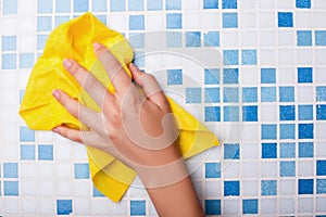 Cheerful maid is cleaning tiled surface with a