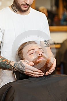 Cheerful male barber is serving his customer