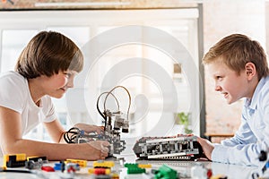 Cheerful male children playing with robotics photo