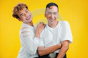 Cheerful male couple smiling on yellow background. Two asian gay standing together and looking at camera