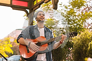 Cheerful male guitarist learning play on street