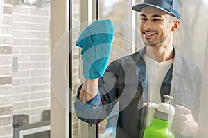 Cheerful male person cleaning window