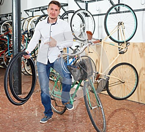 Cheerful male standing with bicylce tires