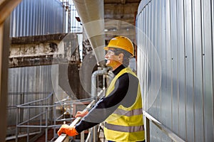 Joyful man engineer standing near metal pipe at factory