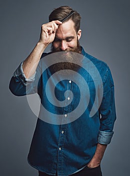 Cheerful man in beard combing his hair