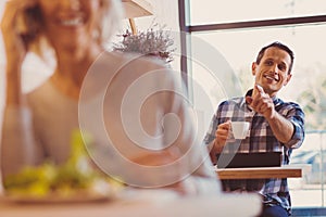 Cheerful man calling up a waiter and asking for refill