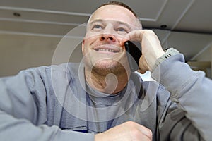A cheerful man is captured enjoying a conversation on a mobile phone. The sincere smile on his face reflects the