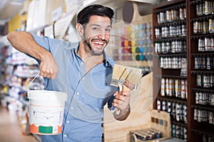 Cheerful man choosing brushes and varnishes