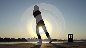 Cheerful man dances jive on a river bank in summer in slo-mo