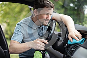 Cheerful man dusting car interior